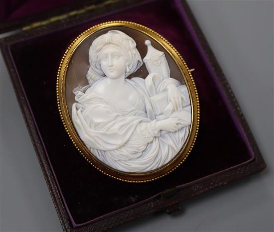 A cased yellow metal and carved oval cameo brooch, decorated with the figure of a lady with an urn, 57mm.